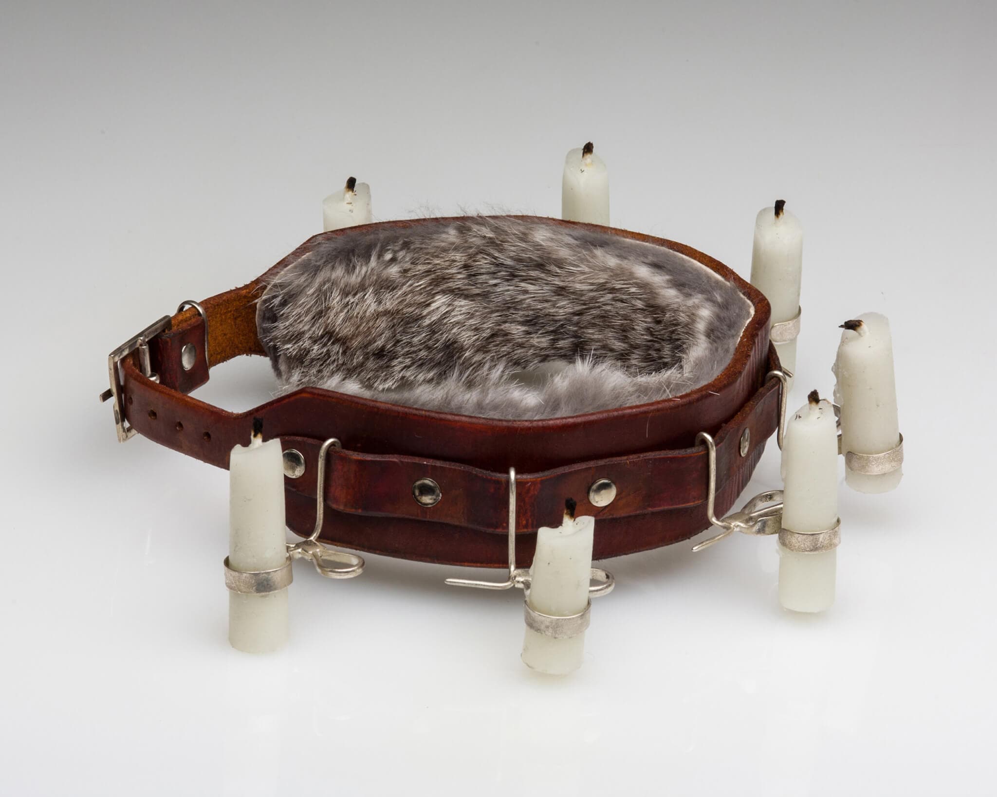 A cluster of fur is surrounded by a brown belt, which in turn is orbited by an arrangement of candles.
