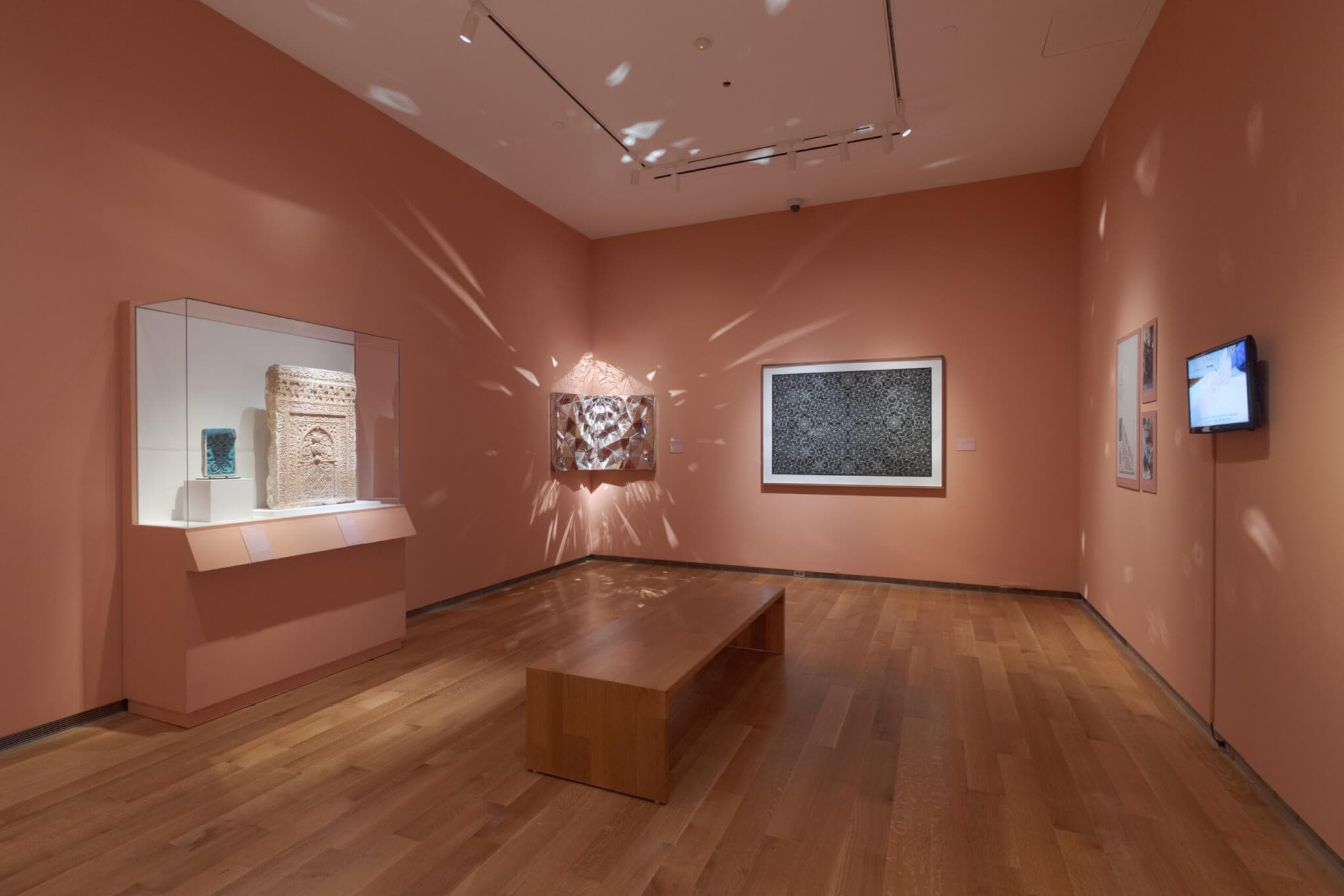 A mirrored artwork radiates light onto the walls of a gallery.